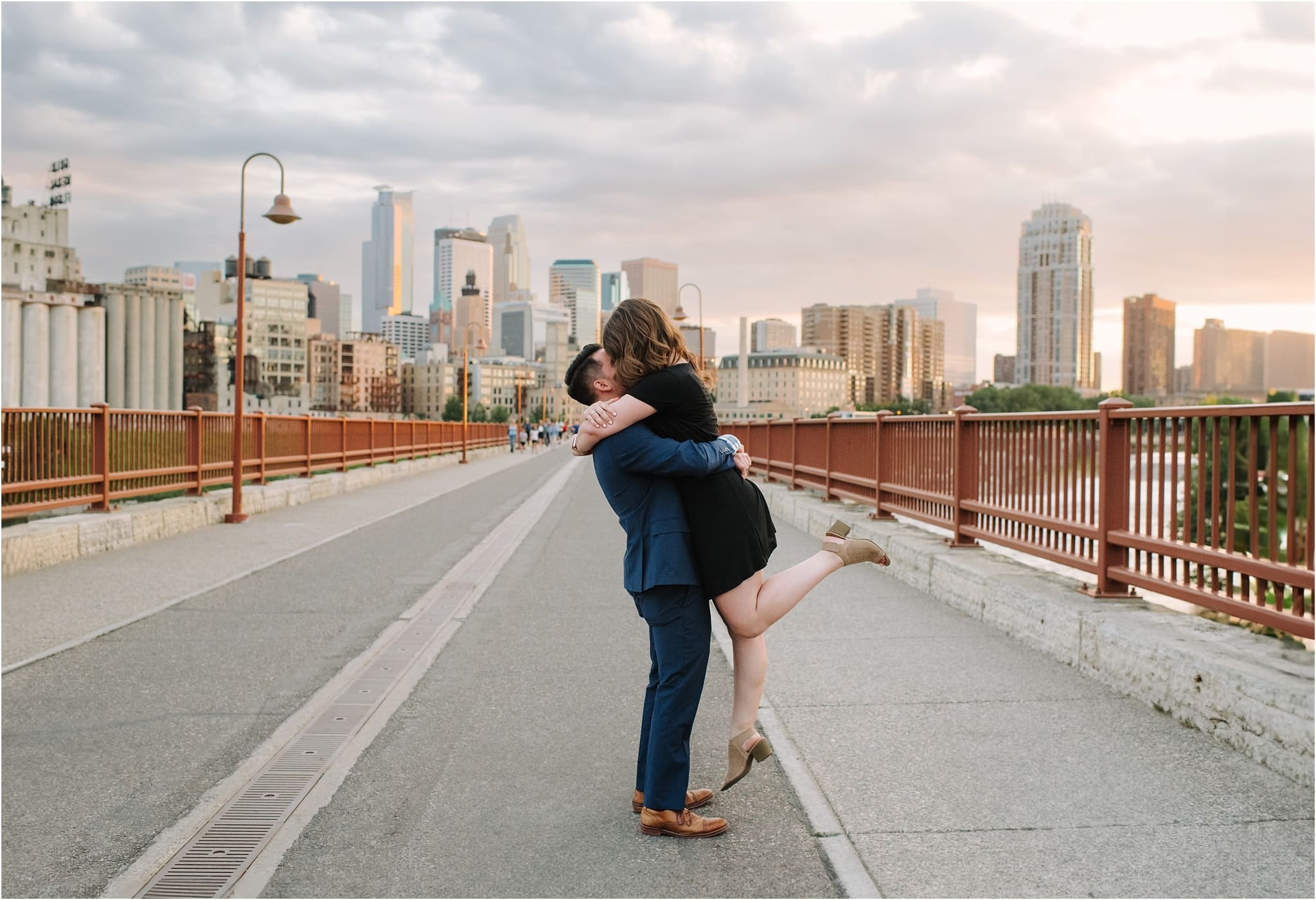 newly engaged couple on stone arch bridge at sunset