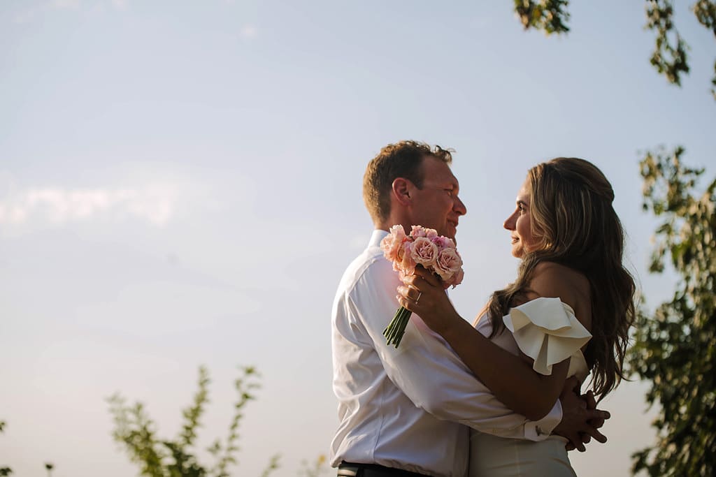 newlyweds embrace in front of clear skies
