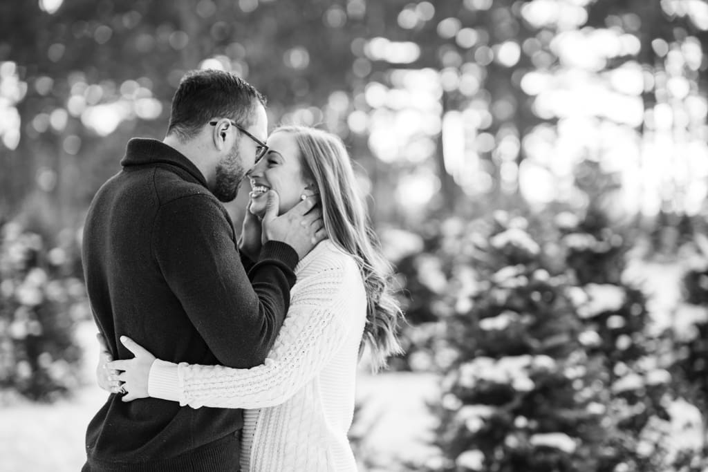 man and woman embracing in snowy tree farm minneapolis